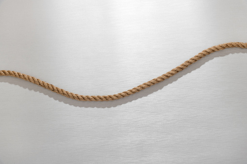Top view of curved natural jute rope placed on gray table in sunlight