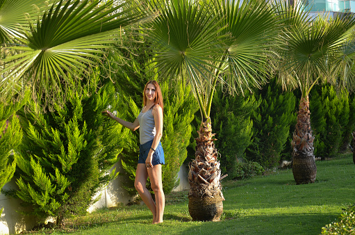 Portrait of a slender woman 30-35 years old surrounded by palm trees. The concept of rest, travel.