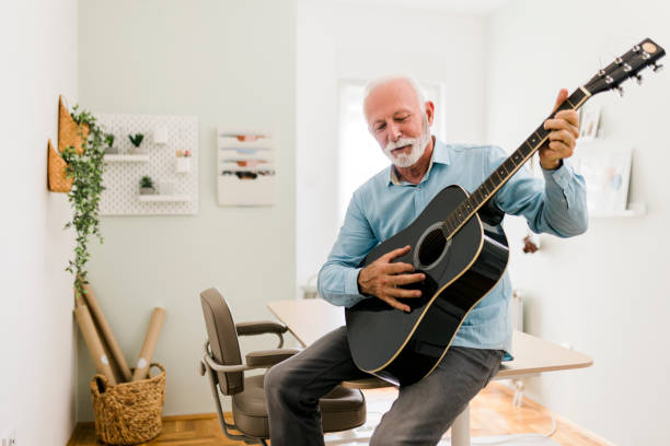 istock Senior male playing guitar at home office 1680523600