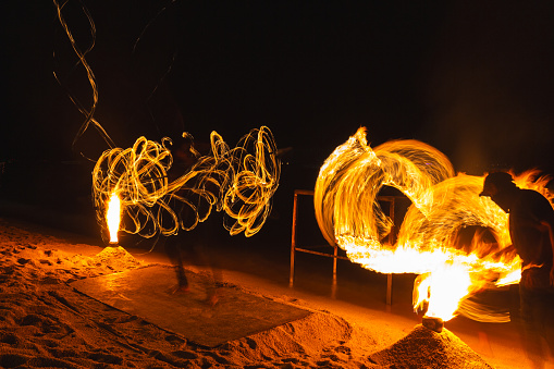 Fire dancers fire dancing show. Fire show on the beach. Dancing man juggling fire. Koh Samui, Thailand. Fire performance at night.