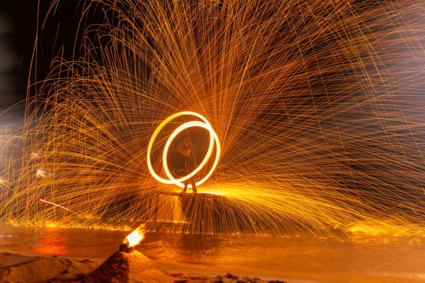 Long exposure shot of the Fire dancers fire dancing show. Fire show on the beach. Dancing man juggling fire. Koh Samui, Thailand. Fire performance at night.