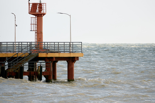 Red lighthouse on the background of the sea. Pier on the embankment. Black Sea, Adler, Russia.