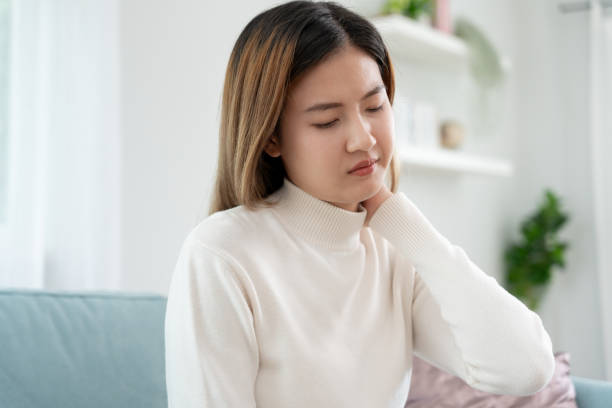 síndromes de consultório, mulher massageando dor no pescoço devido ao trabalho e usando um computador, composto digital de uma coluna focada de dor no pescoço e sintomas de dor no ombro , lesões, cuidados de saúde, médico, miosite - physical injury backache occupation working - fotografias e filmes do acervo