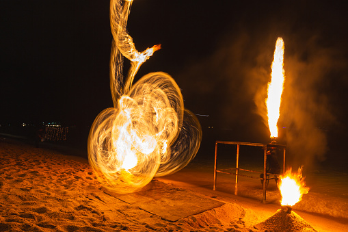 Fire dancers fire dancing show. Fire show on the beach. Dancing man juggling fire. Koh Samui, Thailand. Fire performance at night.