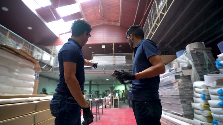 Latin American supervisor talking to young male employee at a batten factory