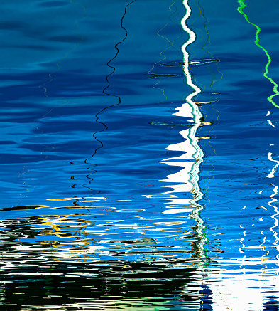 Des reflets de la coque et du mât d'un bateau amarré au port de Nice