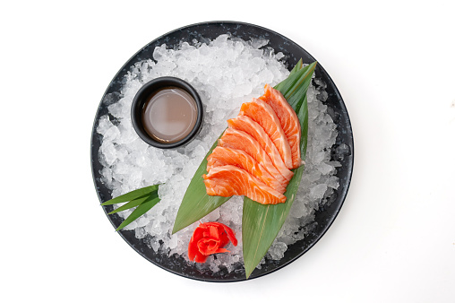 Salmon sashimi plate with sauce on ice isolated