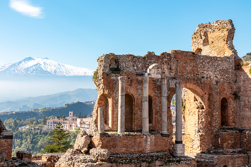 Panoramic view of snow capped Mount Etna volcano on a sunny day seen from the ancient Greek theater of Taormina, island Sicily, Italy, Europe, EU. Travel destination at the Mediterranean sea. Tourism