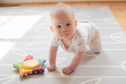 Cute little caucasian baby girl learning how to crawl. Baby care. Child development concept. Baby's first year