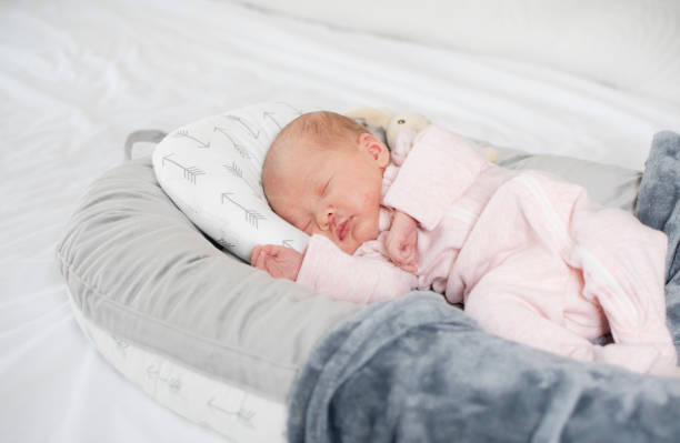 кавказский новорожденный ребенок спит в детском шезлонге. детское гнездышко. - baby animal nest newborn lying down стоковые фото и изображения