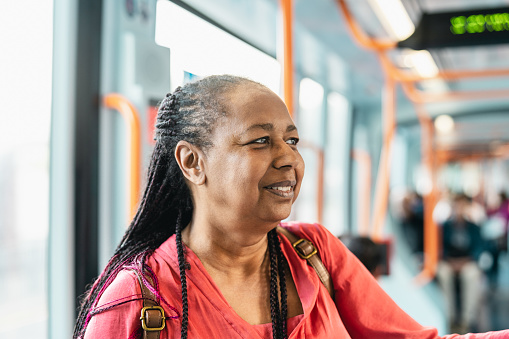 Happy African senior woman traveling with public tram