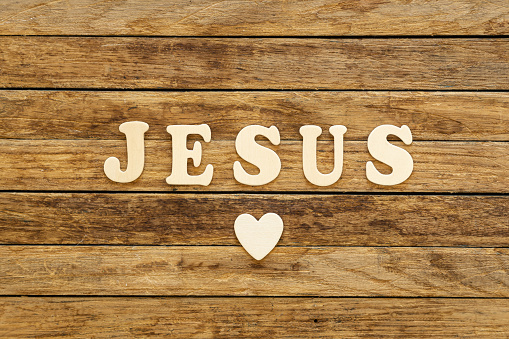 Word Jesus written with wooden letters on wooden background, top view.
