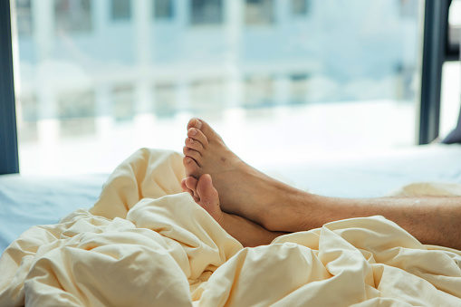 A man's feet lying in bed - family life, lifestyle, healthy lifestyle
