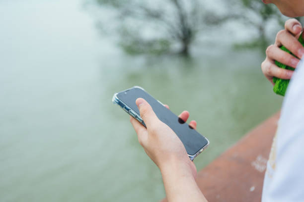 A man holding a mobile phone outdoors by the seaside - technology and life