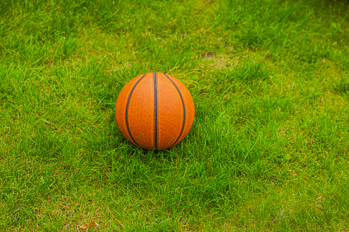 Close-up macro view of basketball on green grass lawn isolated.