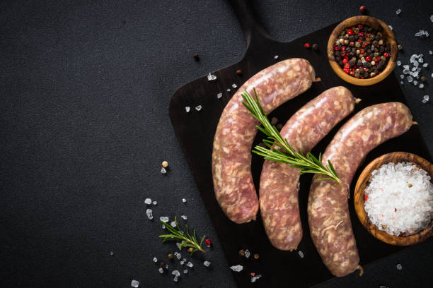 istock Bratwurst or sausages on cutting board with spices at black table. 1680773322