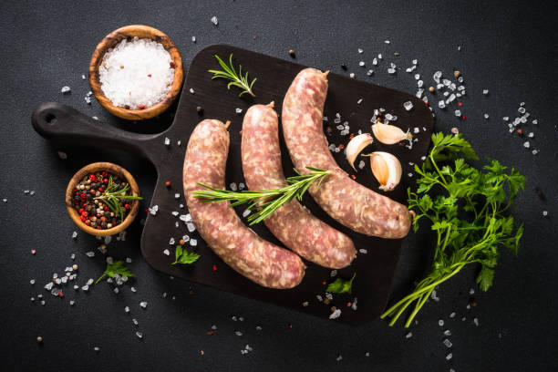 istock Bratwurst or sausages on cutting board with spices at black table. 1680773830