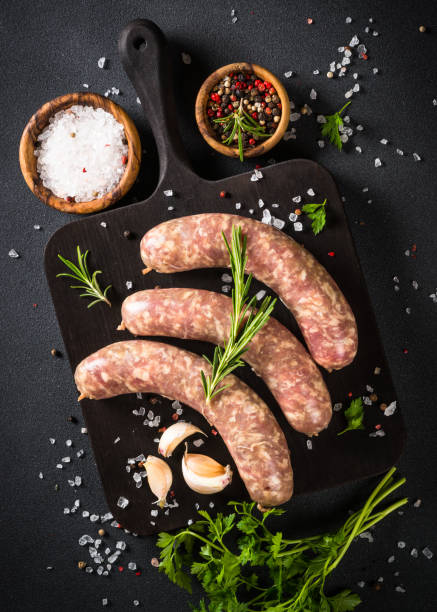 istock Bratwurst or sausages on cutting board with spices at black table. 1680773833