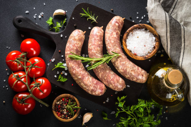 istock Bratwurst or sausages on cutting board with spices at black table. 1680773839