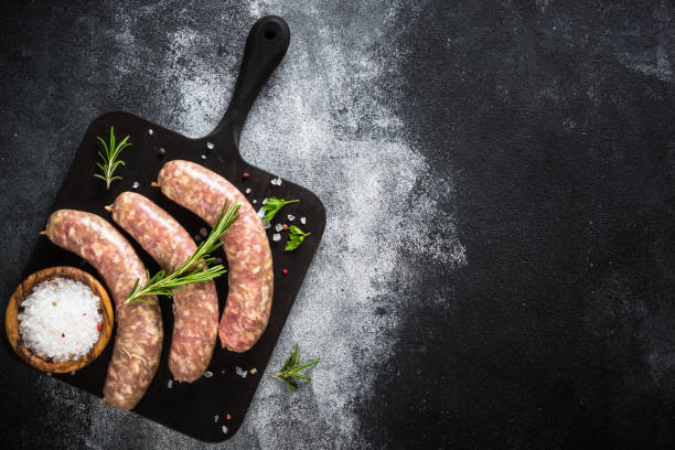 istock Bratwurst or sausages on cutting board with spices at black table. 1680778593