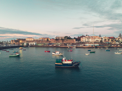 Aerial view of boats and ships in the sea near the port in Cascais, Portugal during sunset