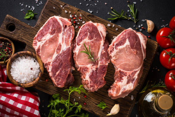 istock Pork meat at wooden board on black table. 1680784549