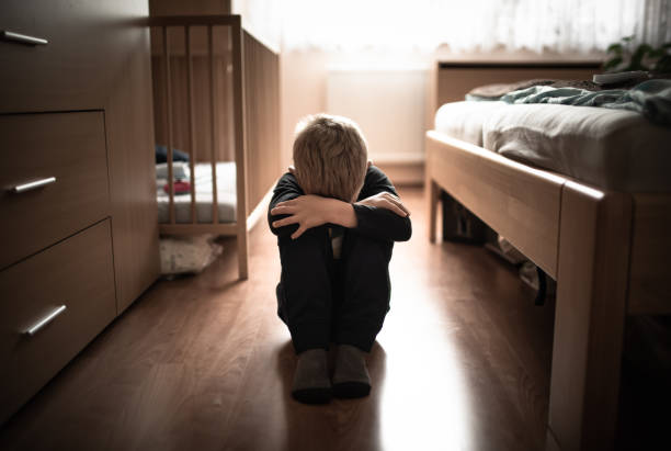 istock Sad little boy sitting on the floor at home. 1680785599