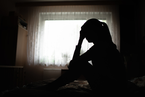 Portrait of Sad depressed young Asian woman sitting alone on the floor at home. Female lost in thoughts, suffer from psychological mental trouble. Mental health and people concept.