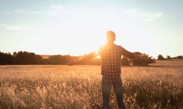 istock Young man with open arms looking up to the sun light. 1680793068