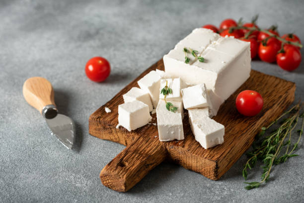 istock Feta cheese cut into cubes with thyme and cherry tomatoes on a wooden board. Side view, selective focus. 1680794739