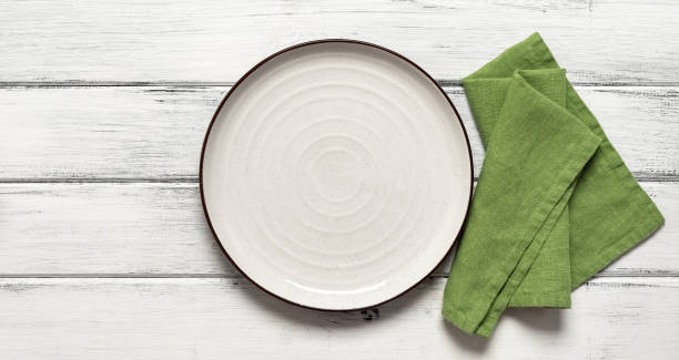 istock Empty white plate with green napkin on white wooden background. Top view, flat lay. Banner. 1680796881