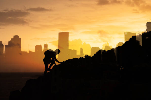 istock Man climbing up mountain against city background. 1680798516