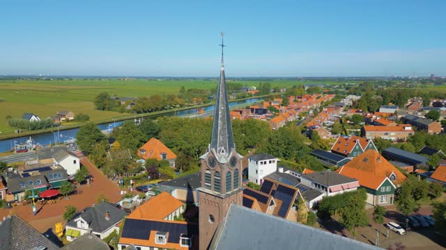 Circle pan to right on church bell tower of cute Dutch village Ilpendam in the Netherlands