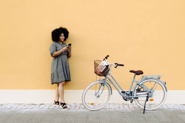 istock Woman using her smart phone while standing near her bicycle 1680846121