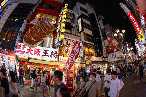Osaka, Japan - September 4, 2023 : People walk through the Dotonbori district of Osaka, Japan. Dotonbori district is a famous tourist destination in Osaka, Japan. Many restaurants are located in Dotonbori district.