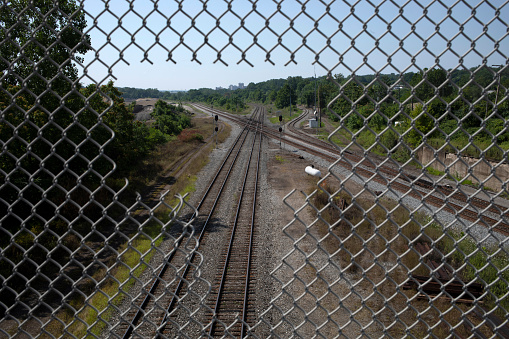 Train tracks viewed overhead through hole in fence in Youngstown, Ohio, United States