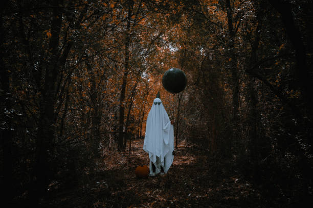 istock Spooky party ghost holding a balloon in the forest 1680878605