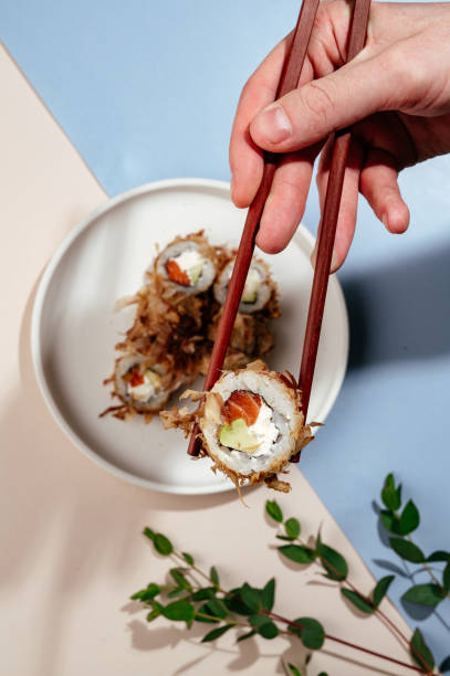 istock a man's hand holds Japanese sushi rolls with chopsticks 1680879167