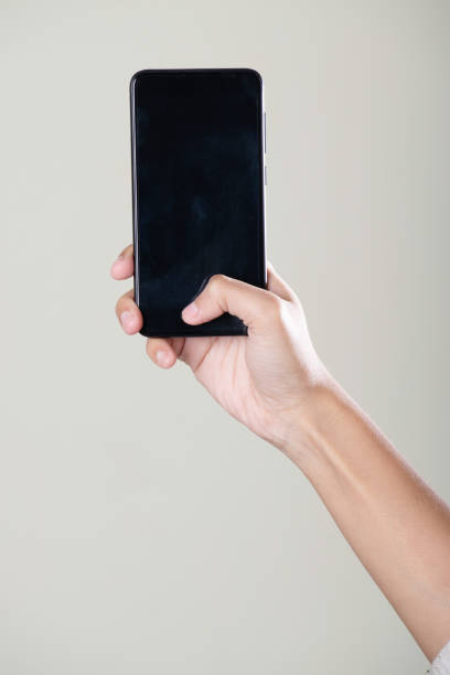 istock Black screen smartphone in hand on grey background 1680879309