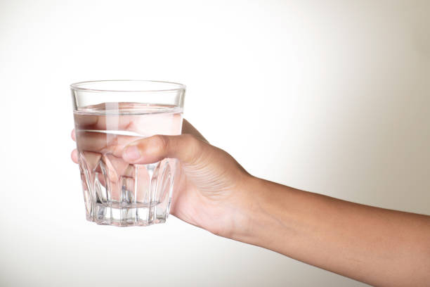 istock Water glass in hand on grey background 1680880388