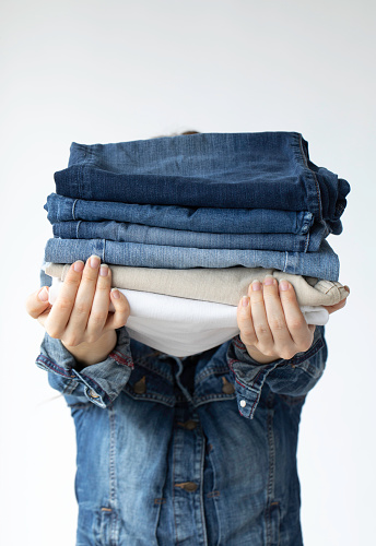 Young woman holding a pile of folded jeans.