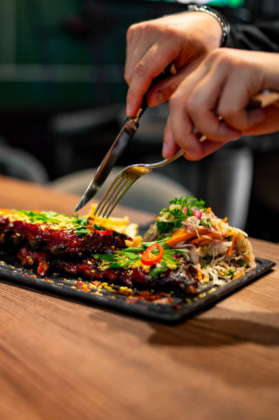 istock man hands with fork and knife eating meat ribs in cafe 1680893447