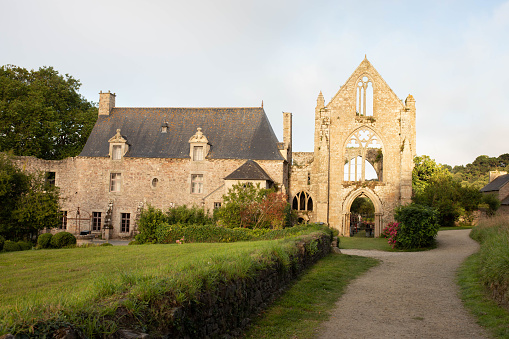The main facade and alleyway of Beauport Abbey, a roofless gothic building located in Paimpol, Cotes d'Armor, Brittany, France. August 2023, sunset view.