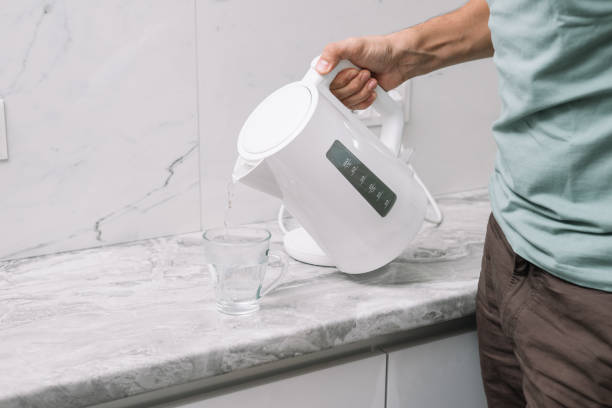 istock a man pours hot water from a white plastic teapot into a mug 1680904325