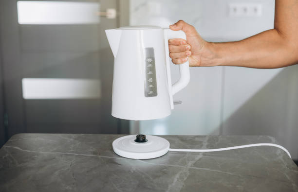 istock Male hands pouring water from a white electric kettle into a mug for making tea 1680904880