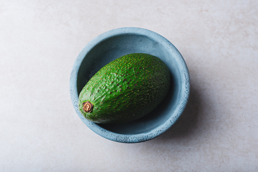 One Green Avocado in Blue Bowl