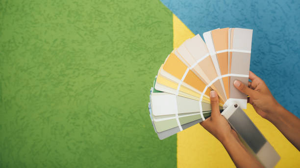 istock Woman choosing color using swatch catalog standing near wall. 1680926908