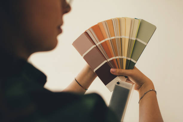 woman choosing color using swatch catalog standing near wall. - home decorator house painter color swatch paint imagens e fotografias de stock