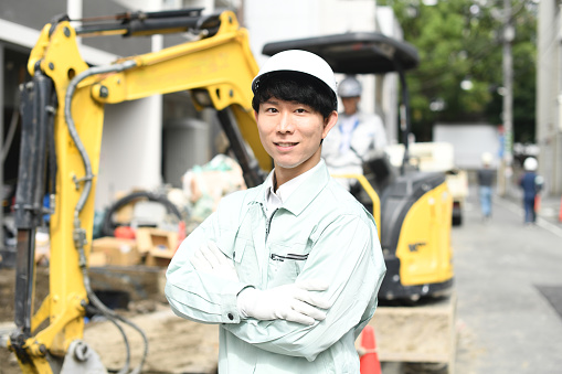 Young Asian male worker with folded arms working at a construction site
