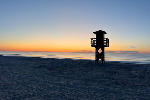 Lifeguard tower on beach on sunset. Miami Beach with lifeguard tower. Rescue tower with lifeguard to watch swimmers in sea to prevent drowning and danger. Colourful Sunset on beach with rescue tower